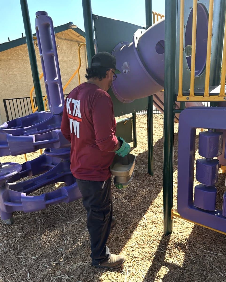 Ruben of KTA IPM treating a playground structure, commercial and public-space pest control in Madera, CA.